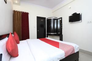 a bedroom with a bed with red pillows and a tv at Capital O Hotel Orchid Inn in Kankhal