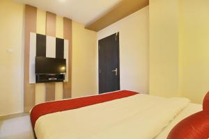 1 dormitorio con 1 cama y TV de pantalla plana en Hotel Rj Grand, en Coimbatore
