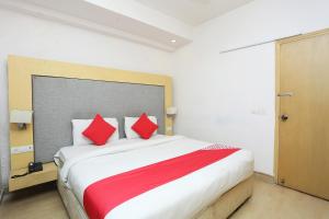 um quarto com uma cama grande e almofadas vermelhas em Super OYO The Avenue Residency Near Leisure Valley Park em Gurgaon
