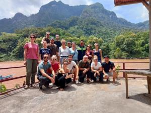 a group of people posing for a picture with mountains in the background at Nam Ou River Lodge in Nongkhiaw
