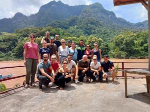 un grupo de personas posando para una foto con montañas en el fondo en Nam Ou River Lodge en Nongkhiaw