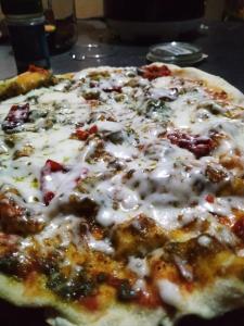 a pizza with cheese and other toppings on a table at Balelangga Bed & Breakfast in Sapit