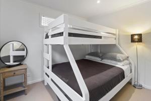 a white bunk bed in a room with a mirror at Goughs Hideaway in Goughs Bay