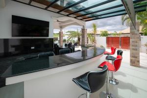 an outdoor kitchen with a bar with red chairs at Orchid Paradise Homes OPV 210 in Hua Hin