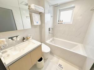 a white bathroom with a sink and a tub and a toilet at ZHome-Modern 3 bedrooms apartment - near NanJing Road in Shanghai