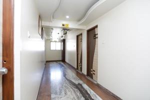 a hallway with white walls and wooden floors at OYO Hotel Bliss Executive Near Sant Tukaram Nagar Metro Station in Chinchwad