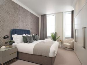 ein Schlafzimmer mit einem großen Bett und einem Stuhl in der Unterkunft Deluxe Mayfair Luxury Apartment in London