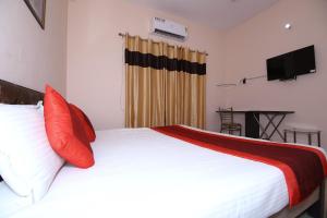 a bedroom with a white bed with red pillows at OYO The Nest in Greater Noida