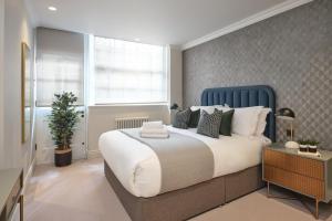 une chambre avec un grand lit et une tête de lit bleue dans l'établissement Uber Mayfair Luxury Apartment, à Londres