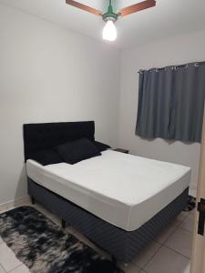 een bed in een kamer met een plafondventilator bij Apartamento encantador 22 in Ubatuba