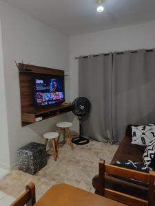 een woonkamer met een bank en een flatscreen-tv bij Apartamento encantador 22 in Ubatuba