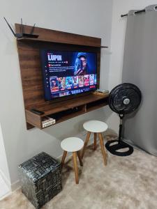 een kamer met twee krukken en een televisie op een plank bij Apartamento encantador 22 in Ubatuba