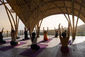 羅威那的住宿－Maha Hills Resort Lovina，一群人在建筑物的屋顶上做瑜伽
