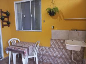 um quarto amarelo com uma mesa e um lavatório em Kitnet Arraial do Cabo, Monte Alto. em Arraial do Cabo