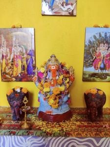 uma estátua de uma divindade sentada numa mesa com dois vasos em WoodPacker Hostel Auroville Pondicherry em Auroville