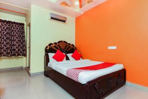 Ce lit se trouve dans un dortoir doté d'un mur orange. dans l'établissement OYO Sindhura Guest House, à Raspari Palao