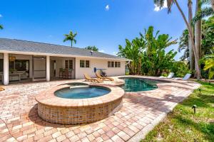un patio trasero con piscina y una casa en Luxury Pool & Spa Home near Beaches & Downtown, en Fort Myers
