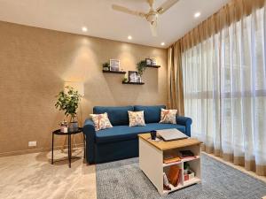 a living room with a blue couch and a window at Lite Stays - Powai in Mumbai