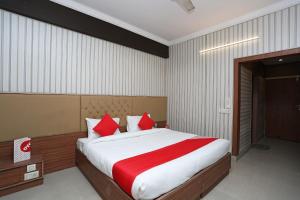 OYO Hotel K-town في Gharaunda: غرفة نوم بسرير كبير ومخدات حمراء