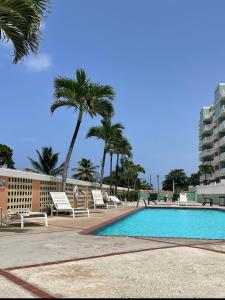 a swimming pool with chairs and palm trees and a building at Paradise Island in Isabela