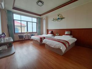 una camera da letto con due letti, un tavolo e una finestra di Meizhou Cloudy B&B a Putian