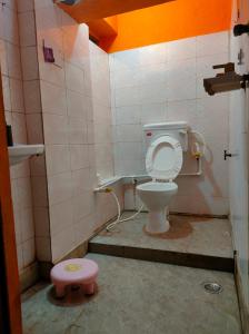 a bathroom with a toilet and a pink stool at Manavi Home Stay in Mathura