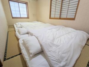 uma fila de camas brancas num quarto com janelas em 1日1組限定の和室style心地よいコンドミニアム em Matsumoto