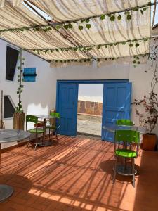 un patio con una puerta azul, sillas y una mesa en Flor de León Café - Hostal, en Barichara