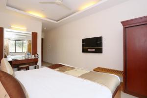 a bedroom with a bed and a tv on the wall at Super Capital O Hotel Dona Castle in Kollam