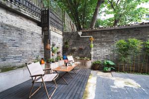 un patio con sillas, mesas y una pared de ladrillo en Shanghai Celebrity Courtyard B&B en Shanghái