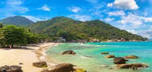 a beach with rocks and the ocean and mountains at The Blue Lion Villa koh Samui - Sea view in Chaweng Noi Beach