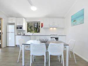 a white kitchen with a table and chairs at Blue Dolphin Holiday Resort in Yamba