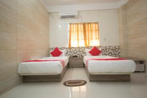 a bedroom with two beds and a window at Capital O Hotel Priyanshu in Siliguri