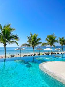 uma piscina com palmeiras e praia em Palace Praia Hotel em Florianópolis
