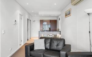 a living room with a leather couch and a kitchen at 412, 162 Hindmarsh Rd, Victor Harbor in Victor Harbor