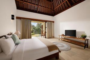 a bedroom with a large bed and a tv in it at OMEGIA Canggu by Nakula in Canggu