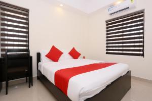 a bedroom with a large bed with red and white sheets at Hotel Better Inn in Ernakulam