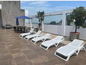 four white lounge chairs and a table and umbrella on a roof at Riversuits#1 Santa Ana in Guayaquil