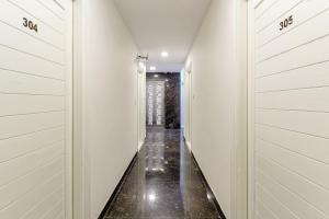 a hallway of a house with white walls and black floors at Capital O Hotel Green Leaf in Gachibowli