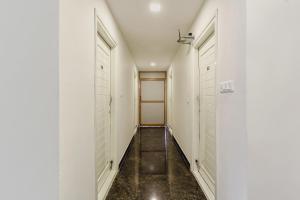 um corredor com paredes brancas e piso preto e duas portas em Capital O Hotel Green Leaf em Gachibowli
