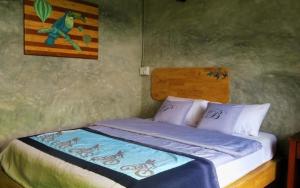 a bedroom with a bed with a painting on the wall at The Picturebook Guesthouse in Mae Sot