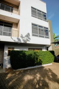 a white building with a hedge in front of it at Close to airport: 2 bedroom home, spacious & cosy in Entebbe