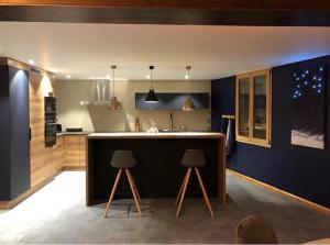 - une cuisine avec un comptoir et deux tabourets dans l'établissement Maison capsule, au Monêtier-les-Bains