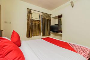een slaapkamer met een bed met rode kussens en een raam bij Parnasala Princely in Rājahmundry