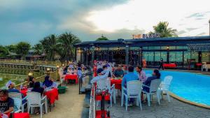 a group of people sitting at tables next to a pool at River Hotel Pattani in Pattani