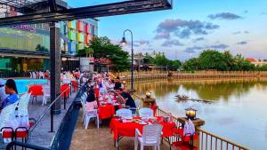 eine lange Reihe von Tischen und Stühlen neben einem Fluss in der Unterkunft River Hotel Pattani in Pattani