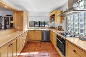 een keuken met houten kasten en een fornuis met oven bij Poolside Serenity - Papamoa Beach Holiday Home in Papamoa