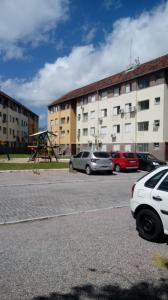 ein Parkplatz mit Autos vor einem Gebäude in der Unterkunft Excelente Apto 2 quartos, condomínio fechado, com vaga estacionamento in Pelotas
