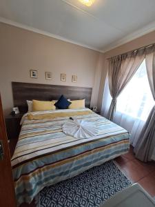 a bedroom with a large bed with a window at Courtlyguesthouse in eMalahleni