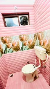 une salle de bains rose avec des toilettes et une fresque florale. dans l'établissement Nature's View Homestay, Travellers, à McLeod Ganj